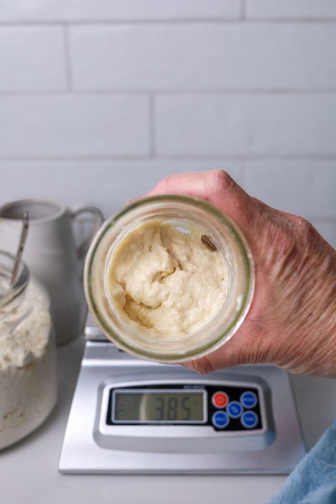 A 16oz jar of sourdough starter that has just been mixed together. It is being held on its side so you can see into the jar.