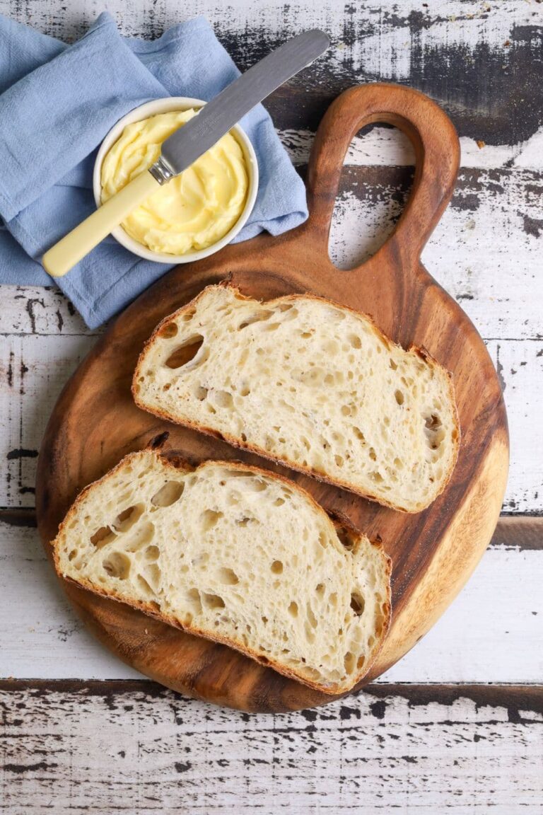A photo of 2 slices of sourdough bread laid out on a round wooden board.
