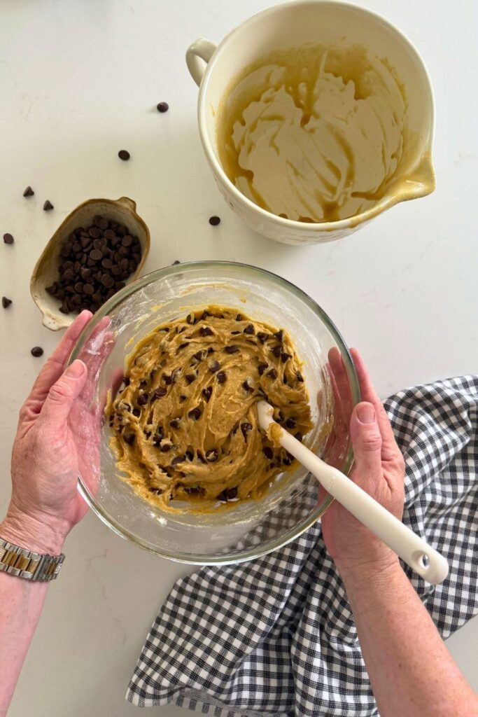 A glass bowl filled with sourdough chocolate chip sourdough cookie dough.