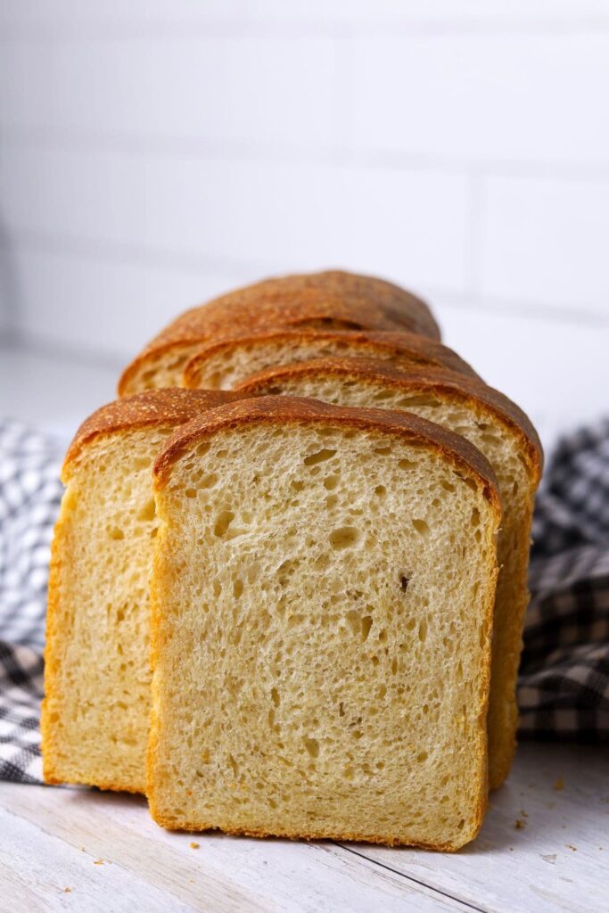 Slices of sourdough sandwich bread standing upright so you can see the soft crumb.