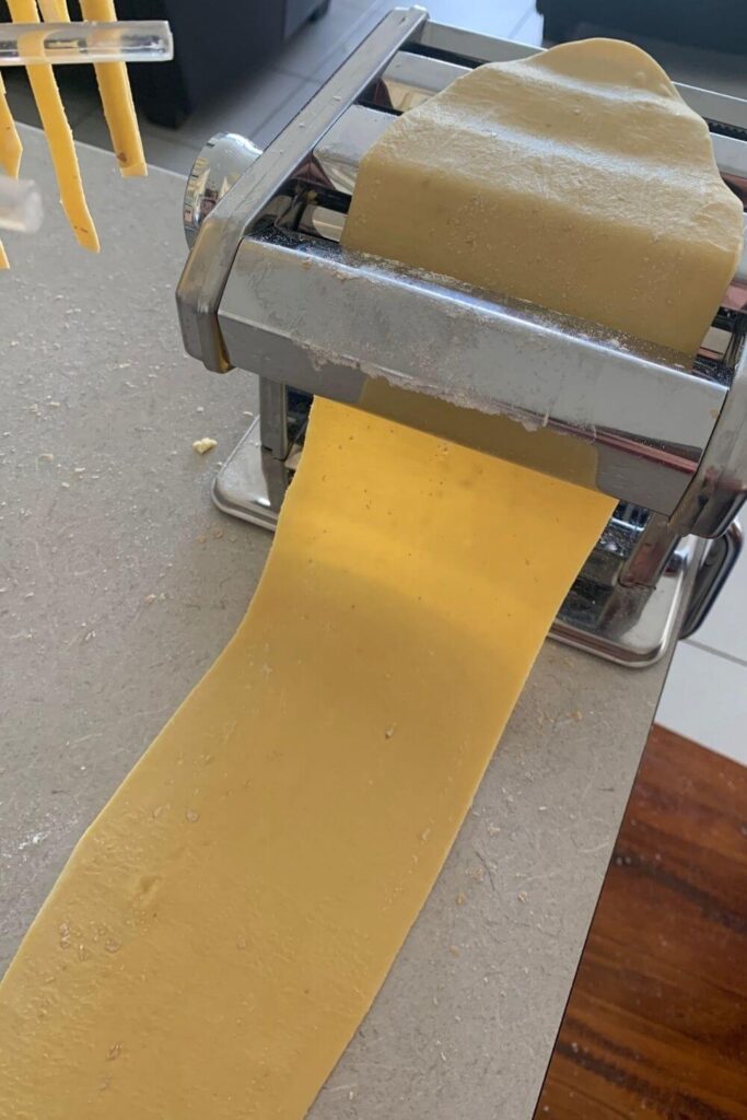 Sourdough pasta being rolled out using a pasta maker.