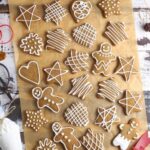 A flat lay of lots of different sourdough gingerbread cookies that have been decorated with white royal icing.