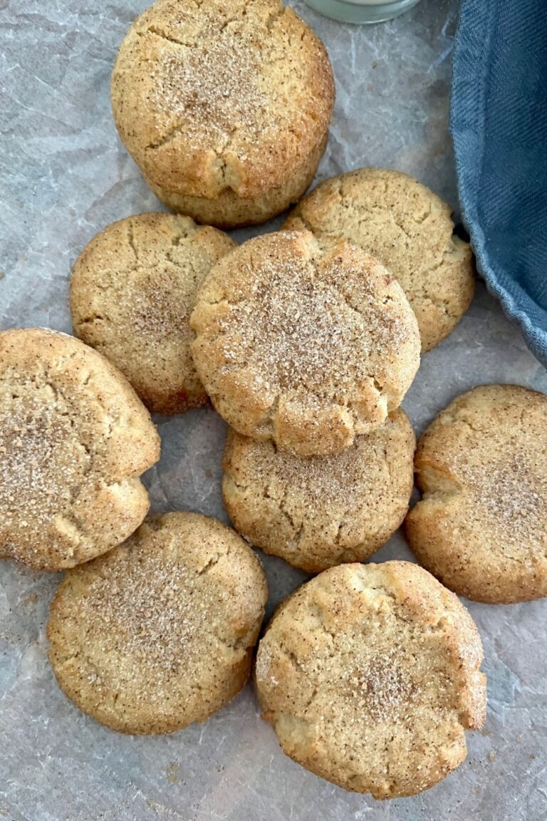 A stash of sourdough snickerdoodles rolled in cinnamon sugar. They've just been baked and arranged on a piece of parchment paper.