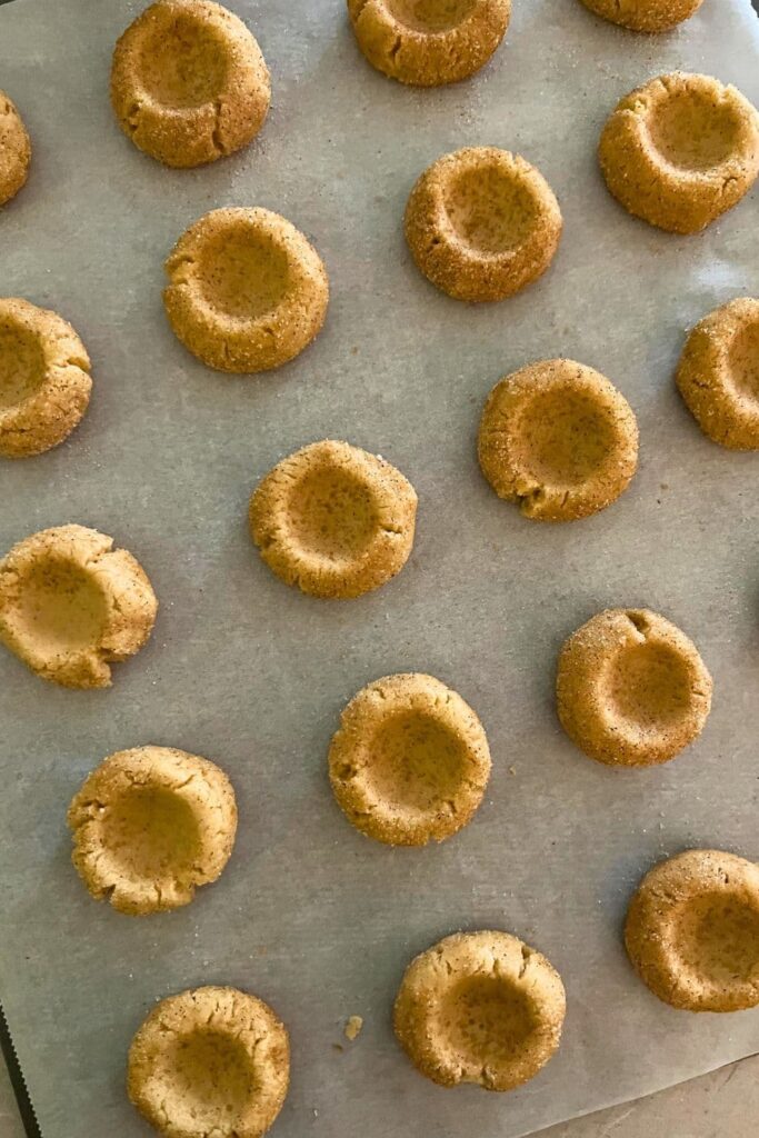 Sourdough snickerdoodle cookie dough balls that have been indented with the back of a spoon.