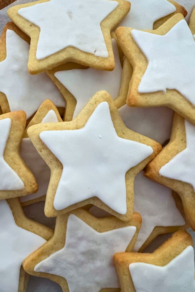A close up image of sourdough sugar cookies cut into star shapes, baked and layered with white fondant.