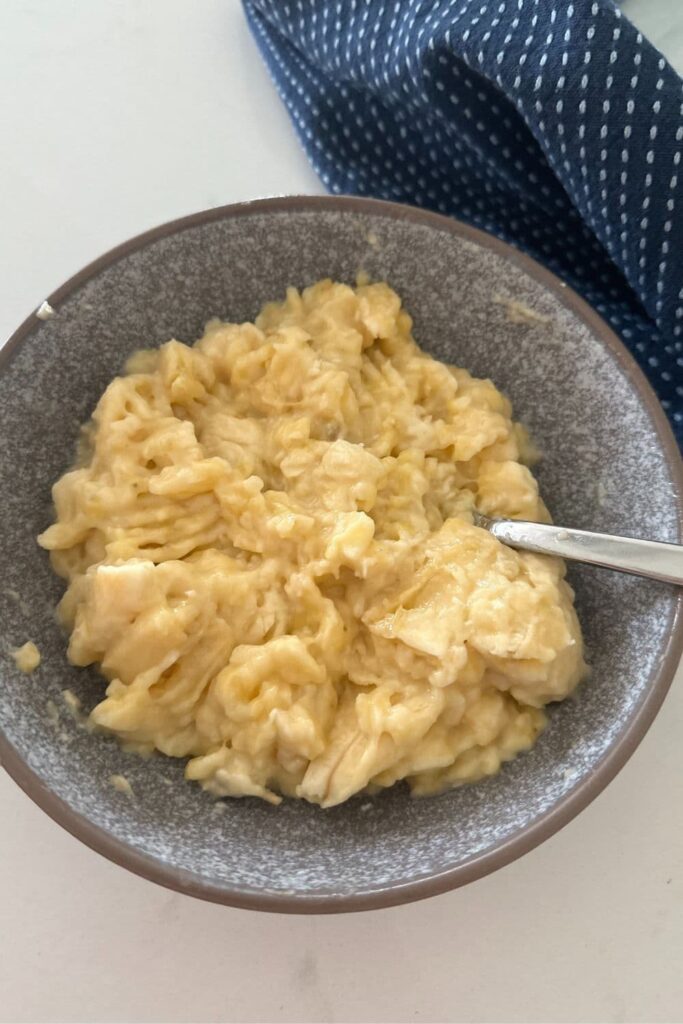 A grey stoneware bowl of mashed banana used to bake sourdough banana muffins.