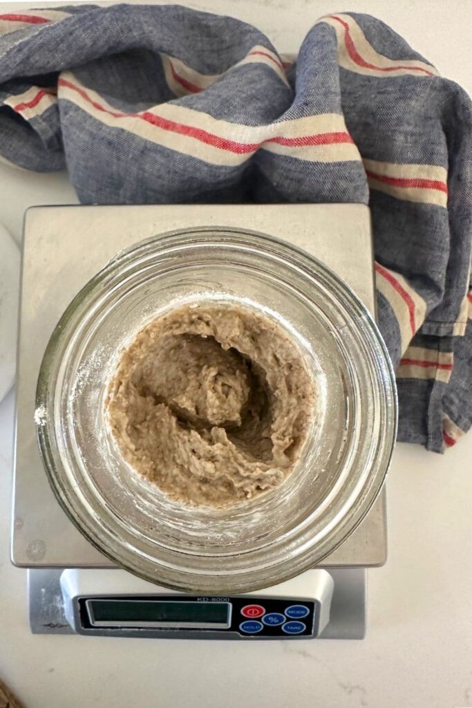 A top down view into a jar of rye sourdough starter that has just been mixed together. It is sitting on top of a scale.