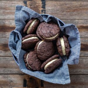 SOURDOUGH CHOCOLATE SANDWICH COOKIES sitting in a blue dish towel on a wooden counter top.