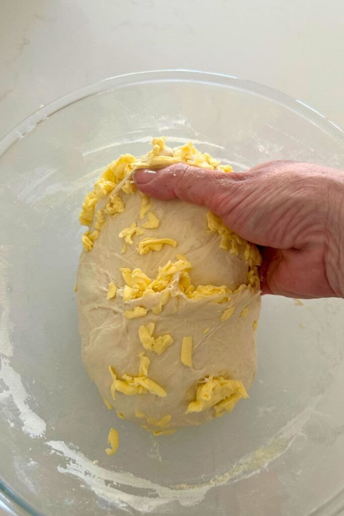 A bowl of sourdough croissant bread dough being stretched and folded.