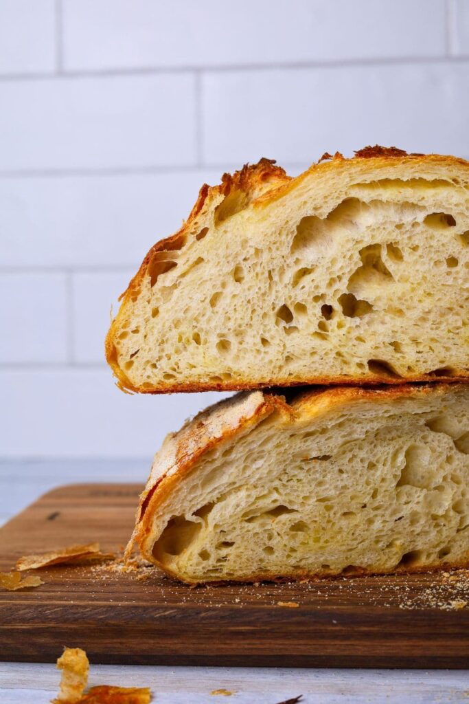 Two halves of a loaf of sourdough croissant bread that have been stacked on top of one another so you can see the tender, buttery crumb inside.