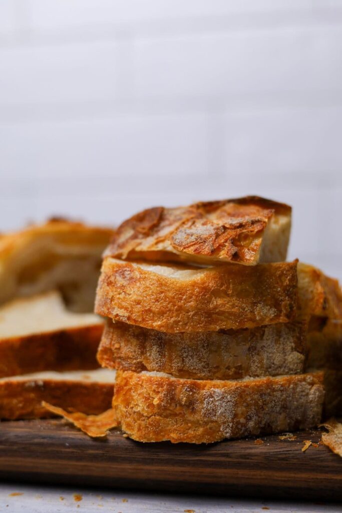 A stack of sourdough slices on their sides showing the edges so you can see the golden, flakey crust on the sourdough croissant bread.