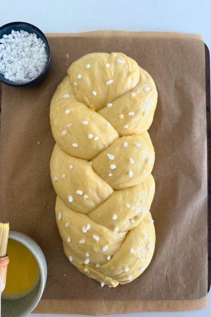 Sweet braided sourdough that has been proofed, egg washed and sprinkled with pearl sugar.