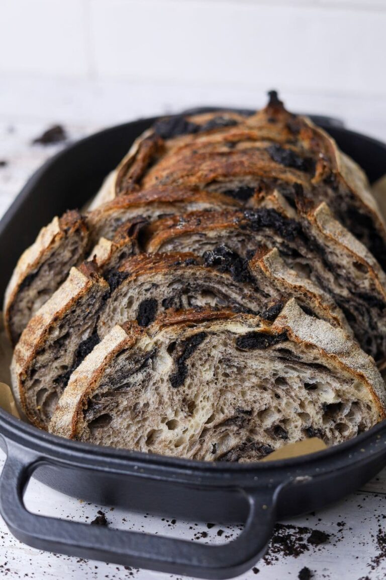 A loaf of cookies and cream sourdough bread that has been sliced and displayed inside a cast iron bread pan.
