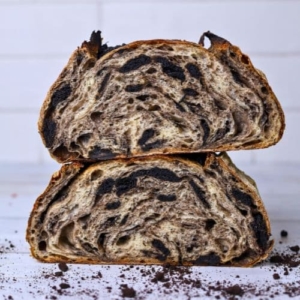 Two halves of a loaf of cookies and cream sourdough bread stacked on top of each other so you can see the crumb inside.