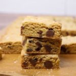A stack of 3 sourdough chocolate chip cookie bars displayed to show their soft, chewy centres laden with chocolate chips.