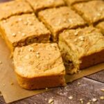A close up of sourdough peanut butter squares, with the one closest to the screen turned out so you can see the texture inside.