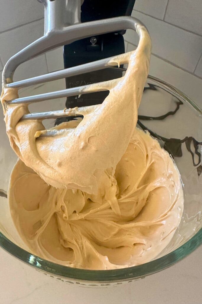 Wet ingredients for making sourdough peanut butter squares that have been whipped until light and fluffy in a stand mixer.