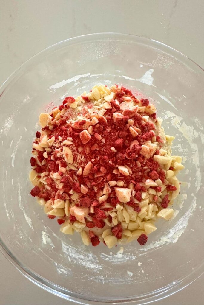 A glass bowl showing the freeze dried strawberries and chocolate chunks tipped on top of the sourdough before stretch and folds.