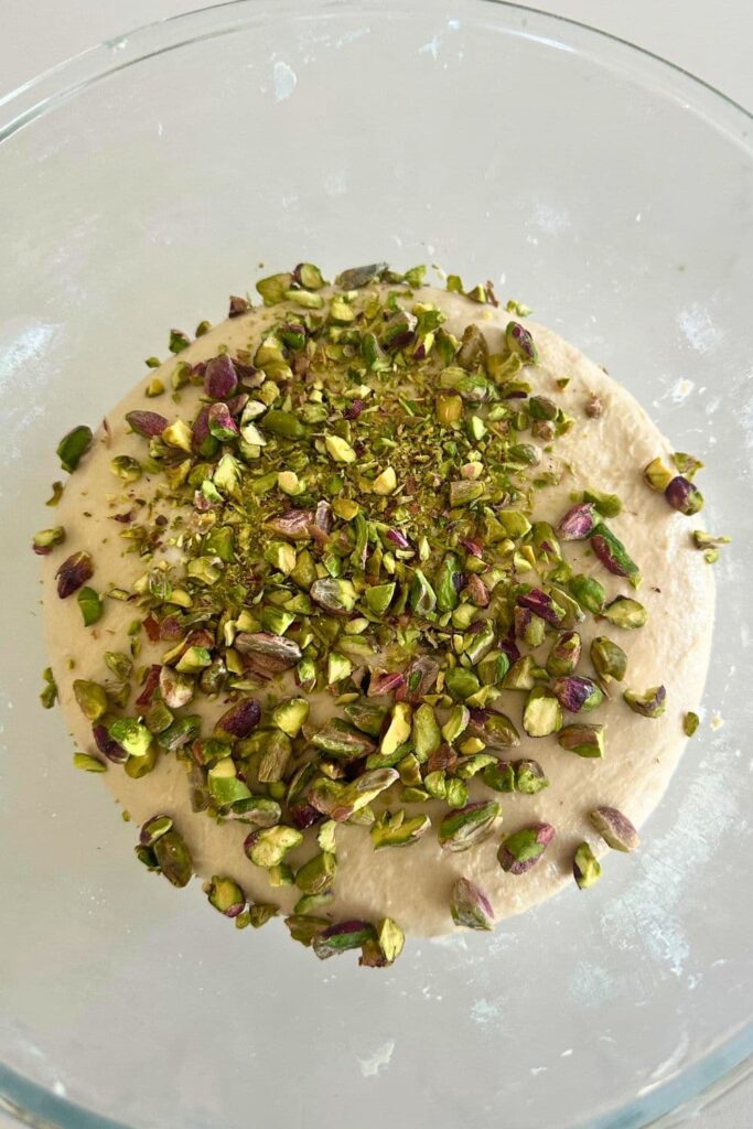A photo of adding the chopped pistachios through the sourdough during stretch and folds.