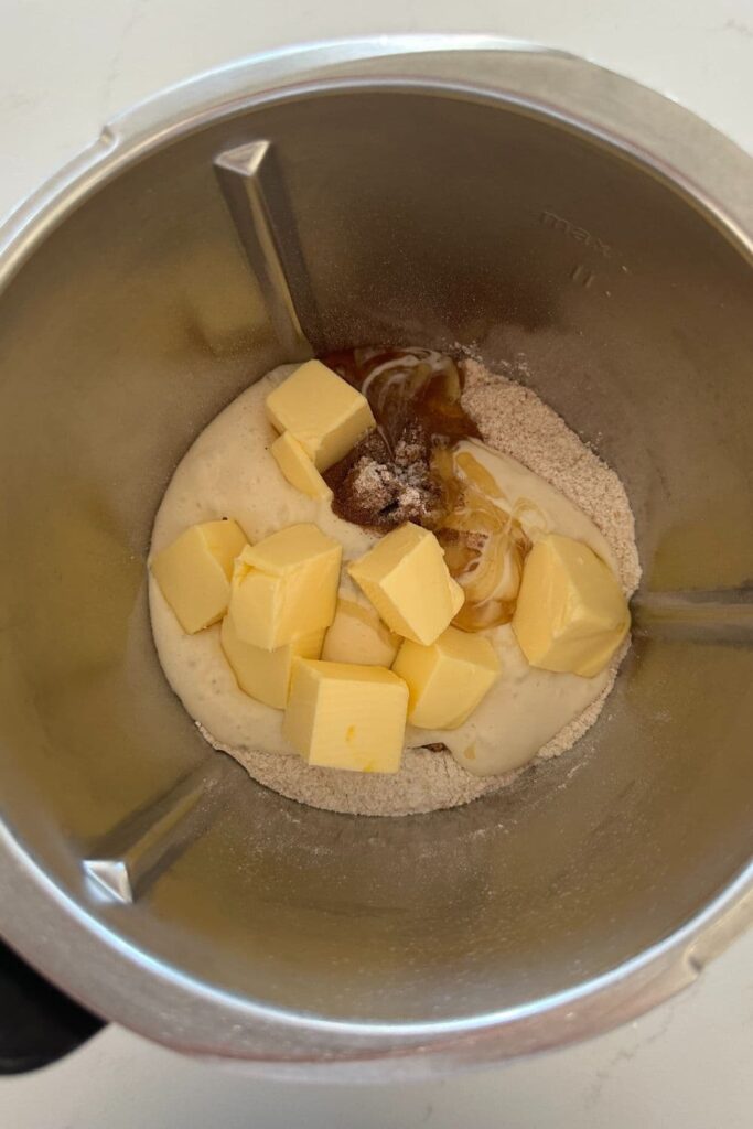 All of the ingredients used to make sourdough graham crackers inside the bowl of a Thermomix (food processor).