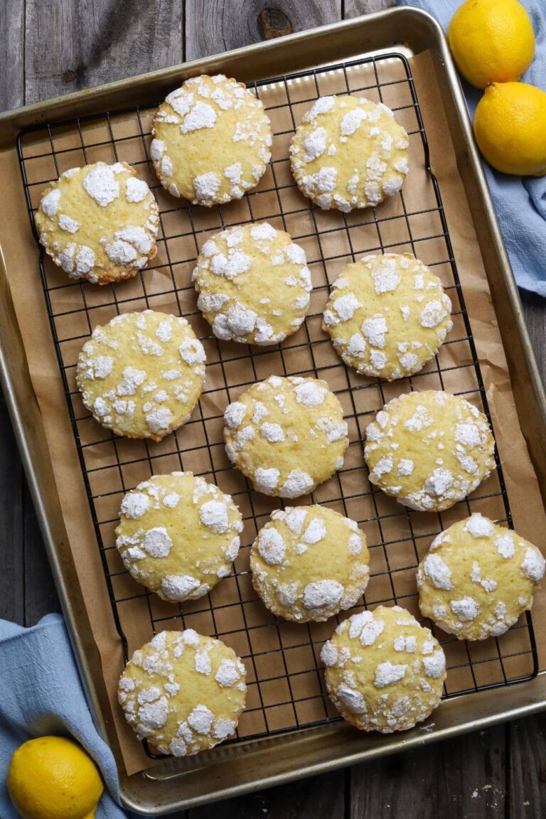 sourdough lemon crinkle cookies on a cooling rack over parchment paper.