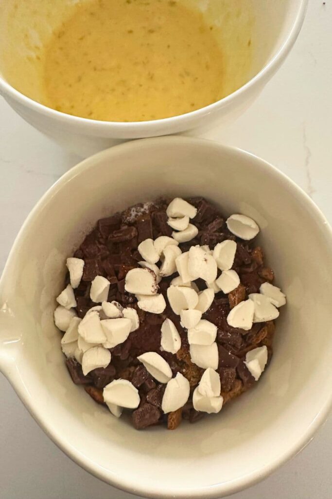 A cream bowl filled with the dry ingredients to make sourdough s'mores banana bread. There is also a second bowl containing the wet ingredients.