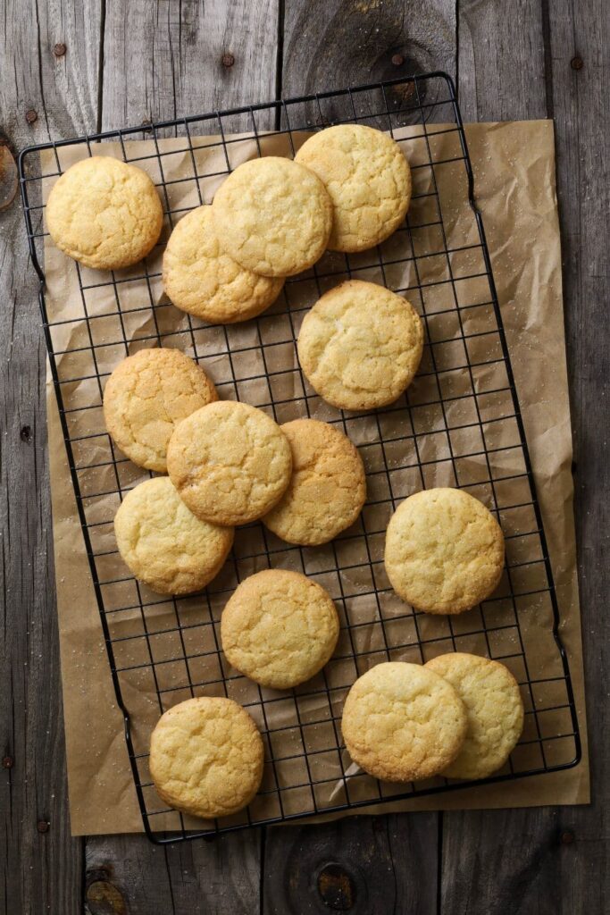 Sourdough vanilla wafers laid out on a black wire cooling rack. There is a piece of parchment paper under the wire cooling rack.