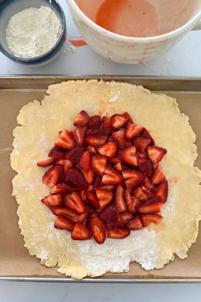 Sourdough strawberry galette with the strawberry filling at the centre, but the pastry has not been folded up yet, so it's sitting open on the baking tray.