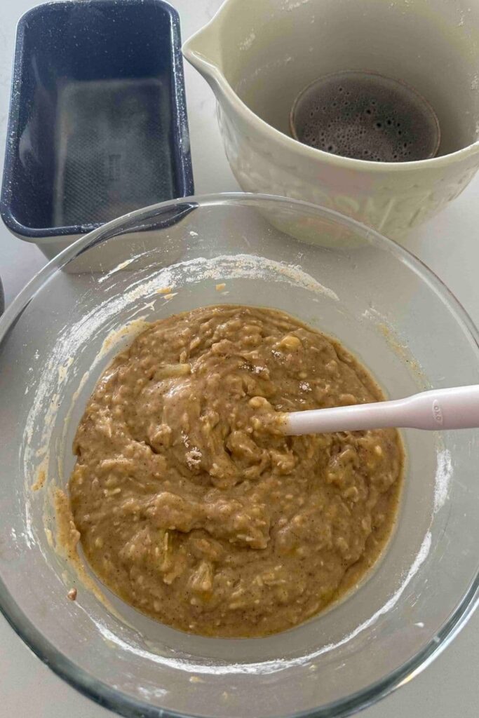 Sourdough Hawaiian banana bread batter mixed together in a glass bowl with a spoon.