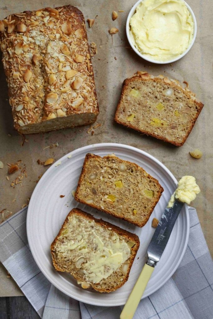 Sourdough Hawaiian banana bread with two slices on a white plate next to a butter knife.