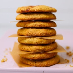 A stack of sourdough peanut butter and jelly cookies balanced on a pale pink baking tray.