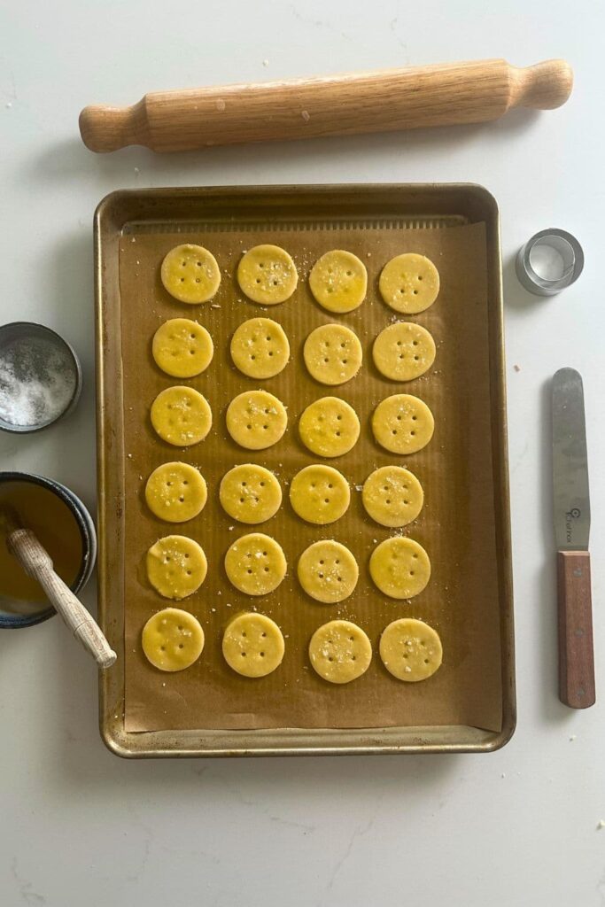 A baking tray with the sourdough Ritz cracker dough cut out in little circles.