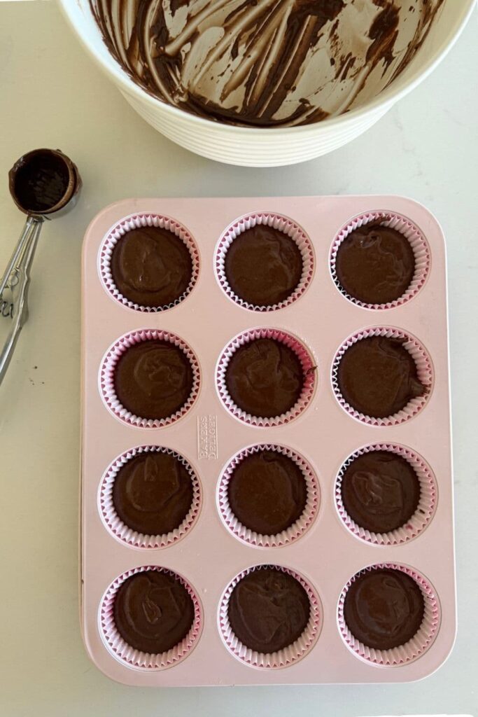 sourdough chocolate cupcake batter in muffin tin lined with paper cups.