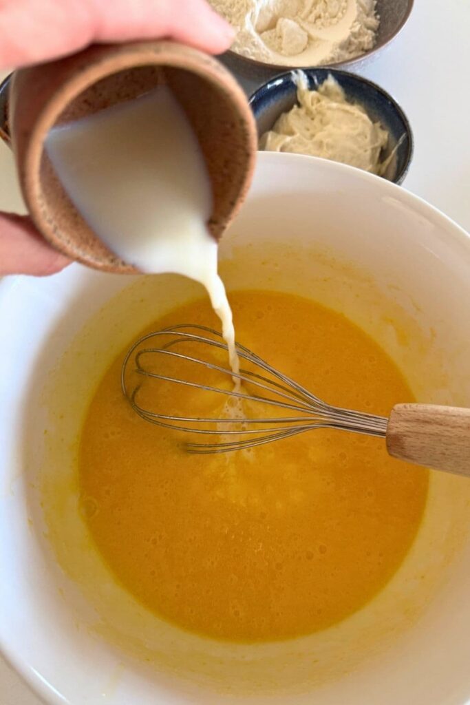 adding milk to bowl with wet ingredients for sourdough chocolate cupcakes.