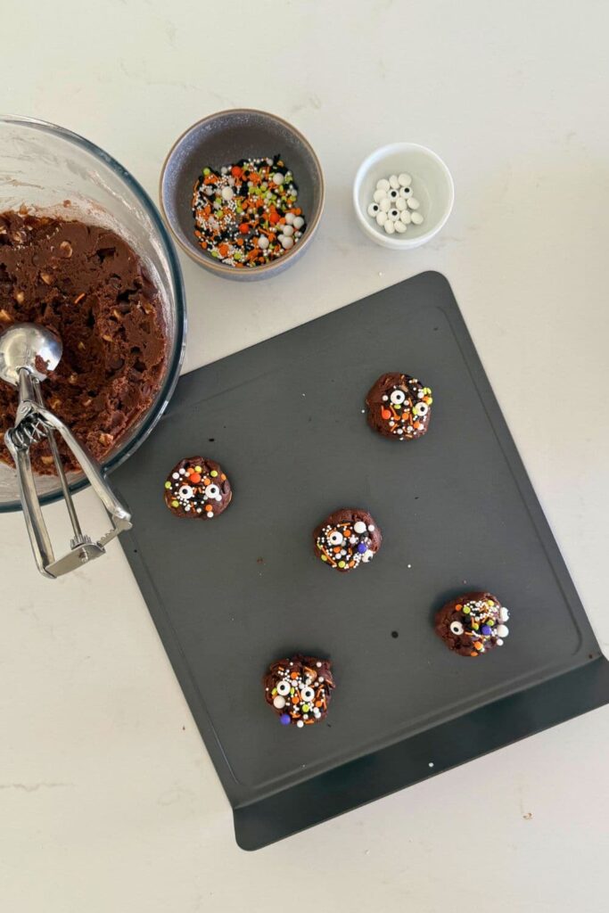 cookie dough balls with Halloween sprinkles on baking sheet to make sourdough Halloween cookies.
