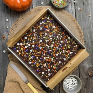 Frosted sourdough halloween frosted brownies in baking pan with Halloween sprinkles on top.
