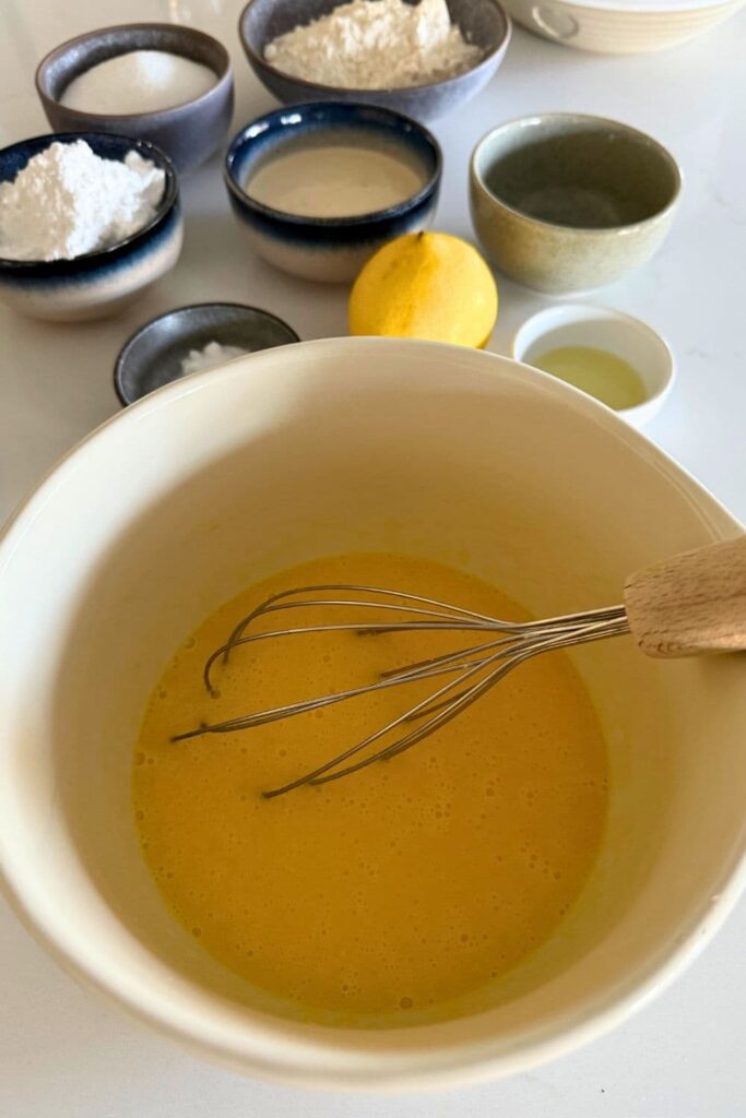 Wet ingredients for sourdough Lemon loaf being mixed together in bowl with a whisk.