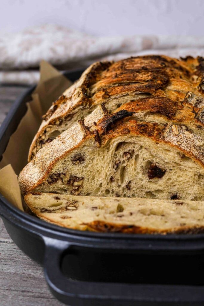 Sourdough maple pecan loaf sliced inside baking dish lined with parchment paper.