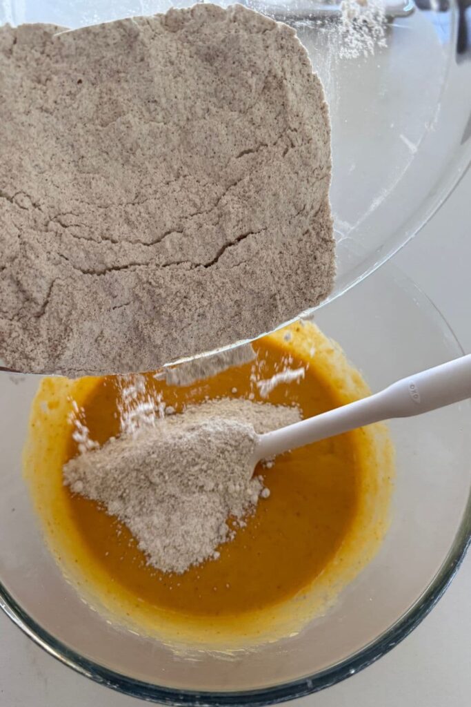 Dry ingredients being tipped into the bowl of wet ingredients.