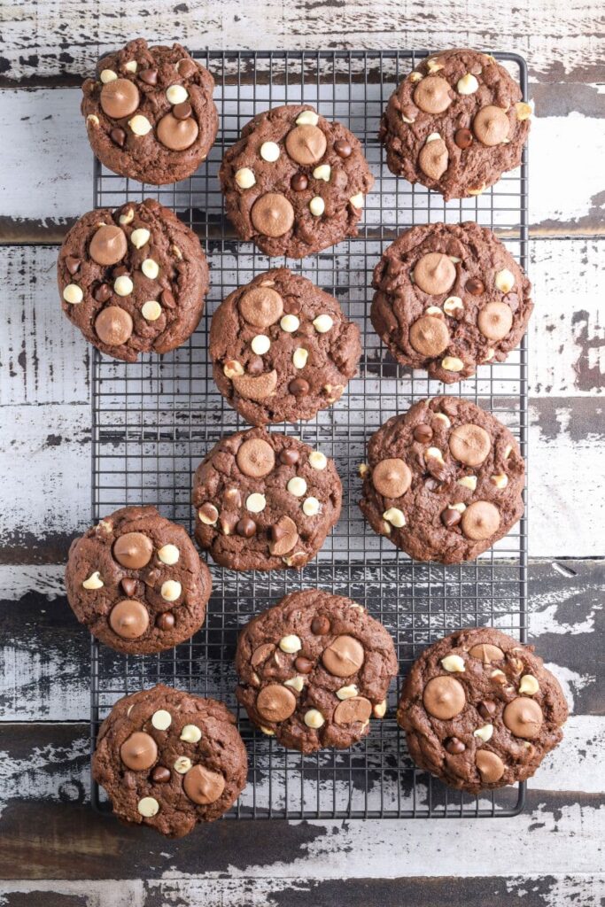 12 triple chocolate sourdough cookies laid out on a wire cooling rack.