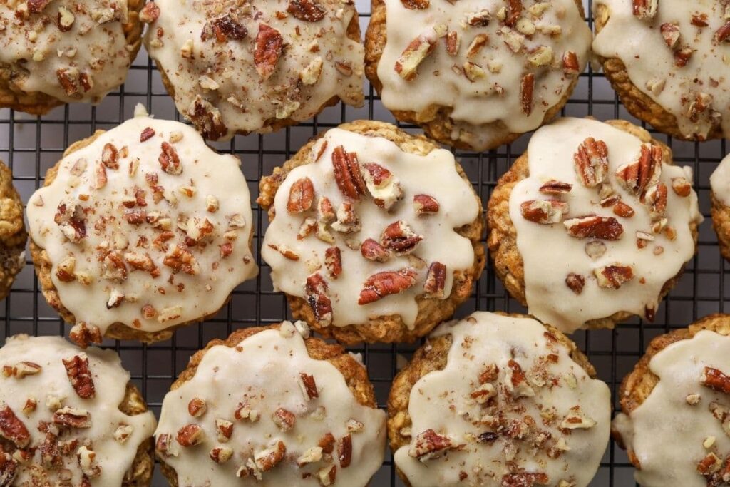 A whole batch of maple pecan sourdough oatmeal cookies with maple butter glaze on a wire cooling rack.