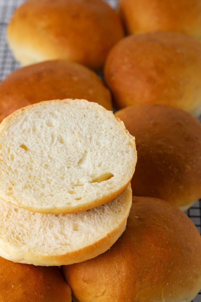 Sourdough burger buns on a wire rack with one sliced open.
