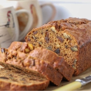 Sourdough date and walnut loaf cake sliced open to show nuts and dates inside the loaf.