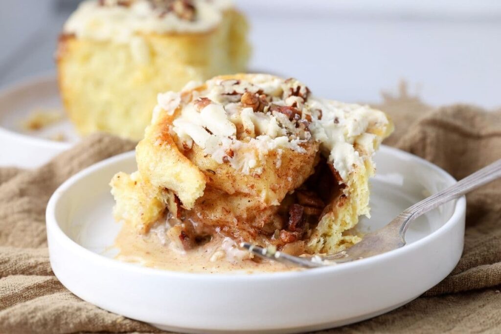 A close up photo of a maple pecan sourdough rolls topped with maple pecan glaze.