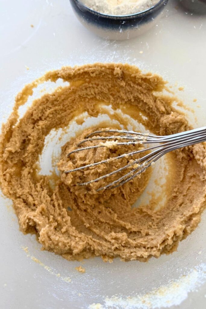 Mixing butter and sugar in a bowl with a whisk for Sourdough Oatmeal Chocolate Chip Cookies.