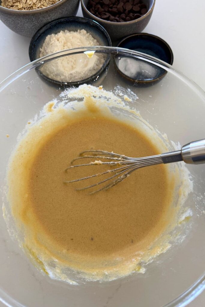 Mixing wet ingredients with a whisk for Sourdough Oatmeal Chocolate Chip Cookies.