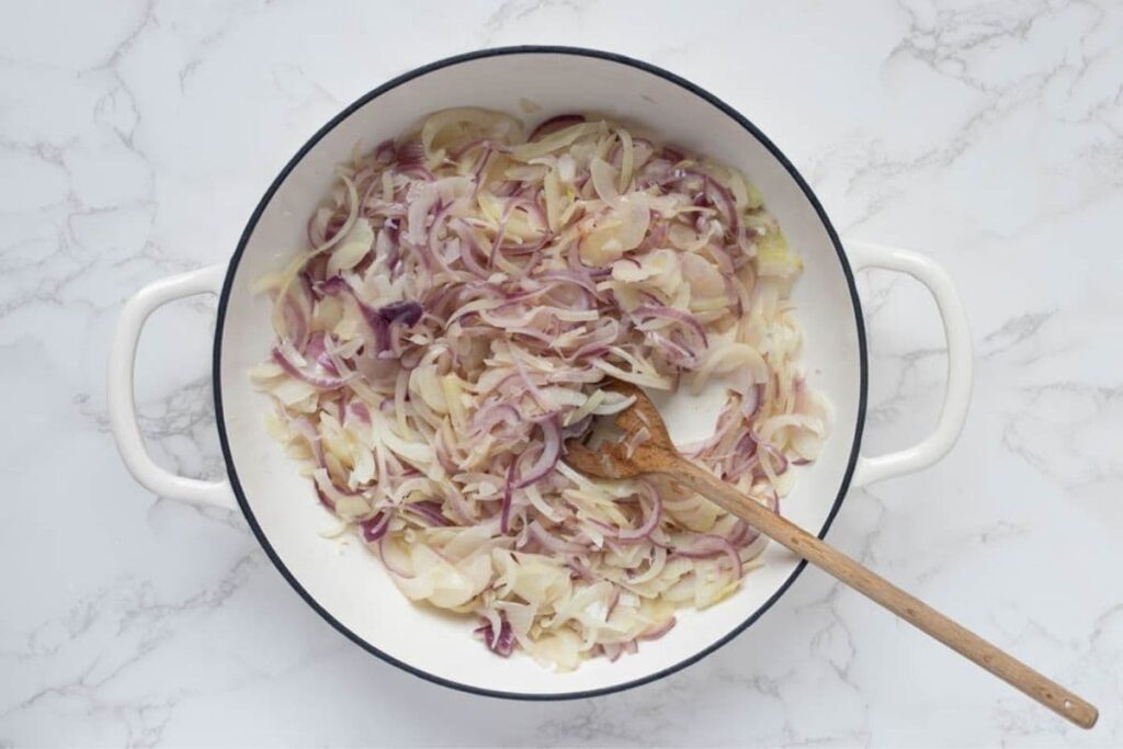 Chopped onions cooking in Dutch oven to make caramelized onion relish.