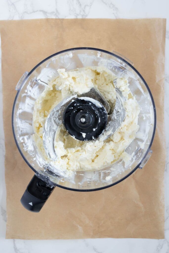 A photo of feta cheese dip inside a food processor taken from above.