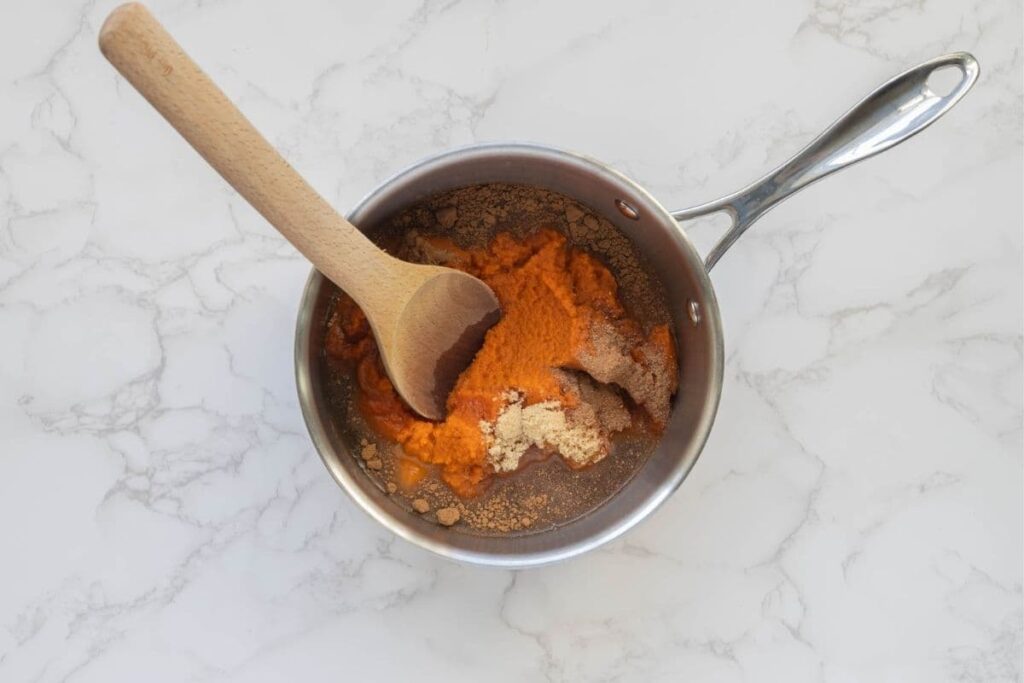 A small saucepan containing pumpkin butter, brown sugar and spices ready to make pumpkin butter.