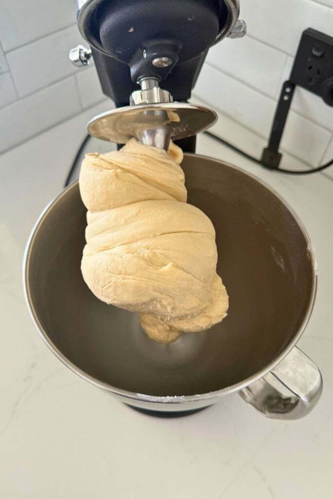 Smooth dough in stand mixer to make sourdough cheese and garlic rolls.